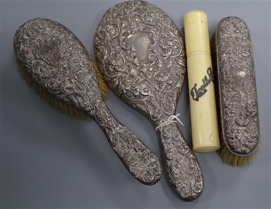 An Edwardian repousse silver three piece mirror and brush set, Mappin & Webb, London, 1905/6 and a toothbrush brush.